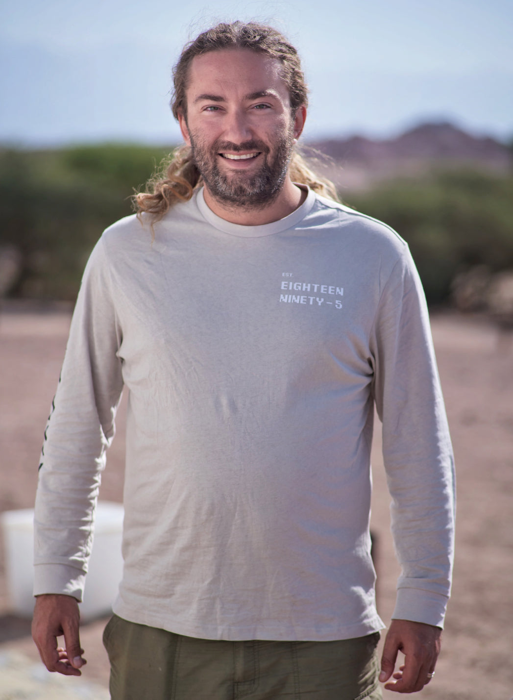 Smiling man with long hair and a beard standing outdoors