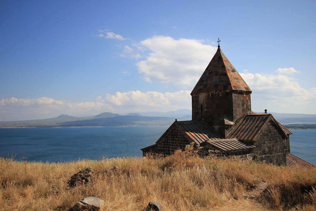 Medieval stone church on a grassy hill above a blue lake