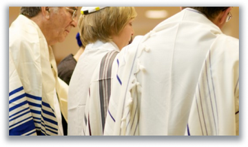 Worshippers wrapped in tallit standing together in prayer