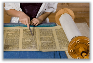 Hand using a pointer to read from an open Torah scroll