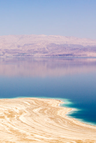 Salt-crusted shoreline of the Dead Sea with the mountains beyond