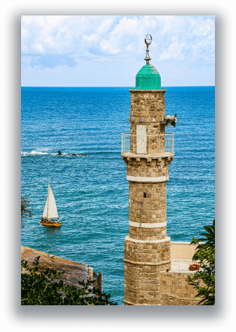 Stone minaret overlooking the blue sea with a sailboat on the water