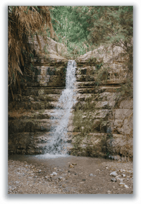 Waterfall cascading over rock terraces in a green desert oasis