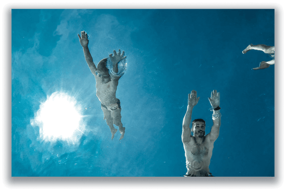 Two men swimming underwater in bright blue water