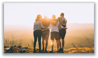 Four friends embracing on a hilltop at sunrise