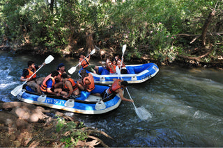 Group rafting down a river through green trees