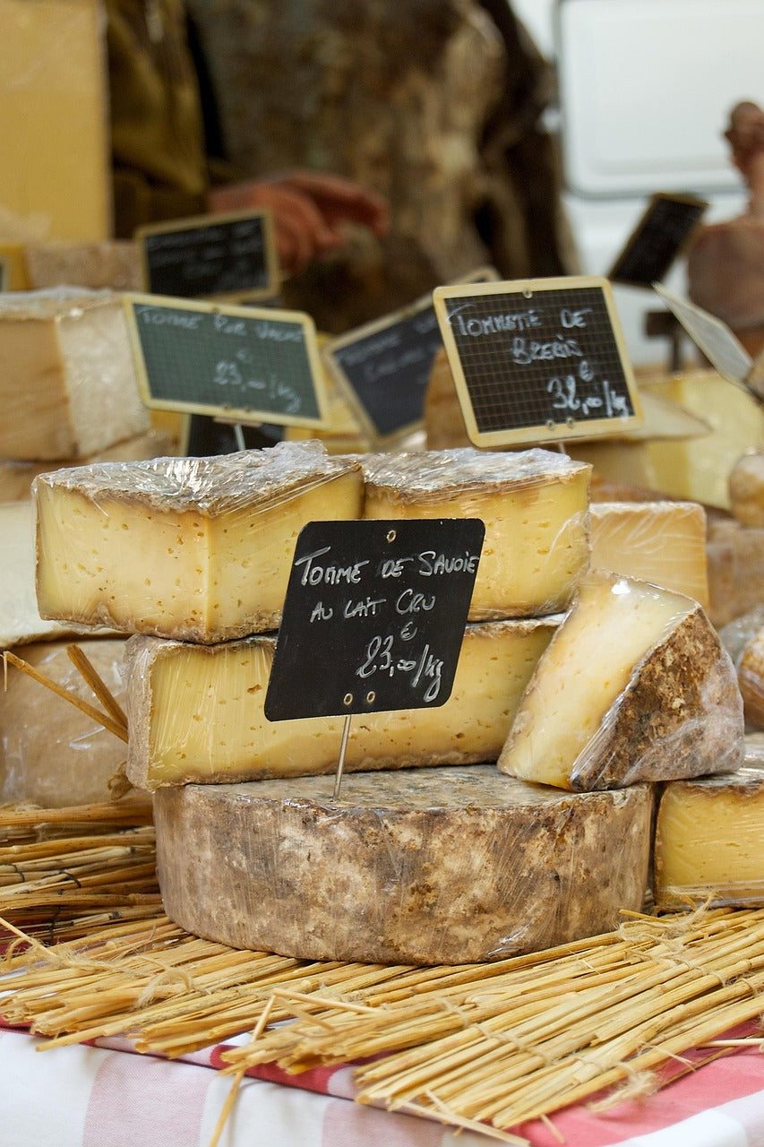 Wheels of cheese with chalkboard labels on a market stall