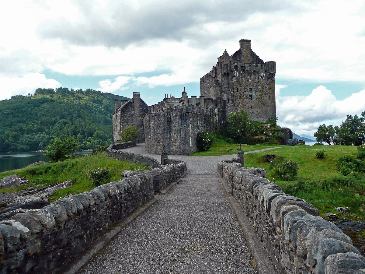 Stone castle at the end of a walled footbridge on a green island