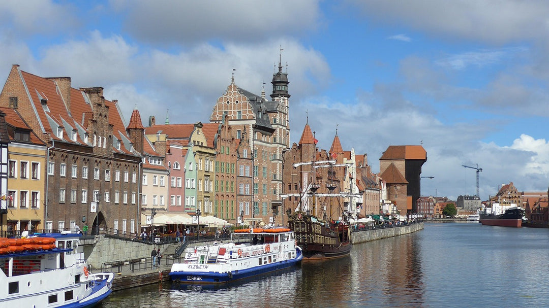 Historic gabled houses and moored boats along a city riverfront