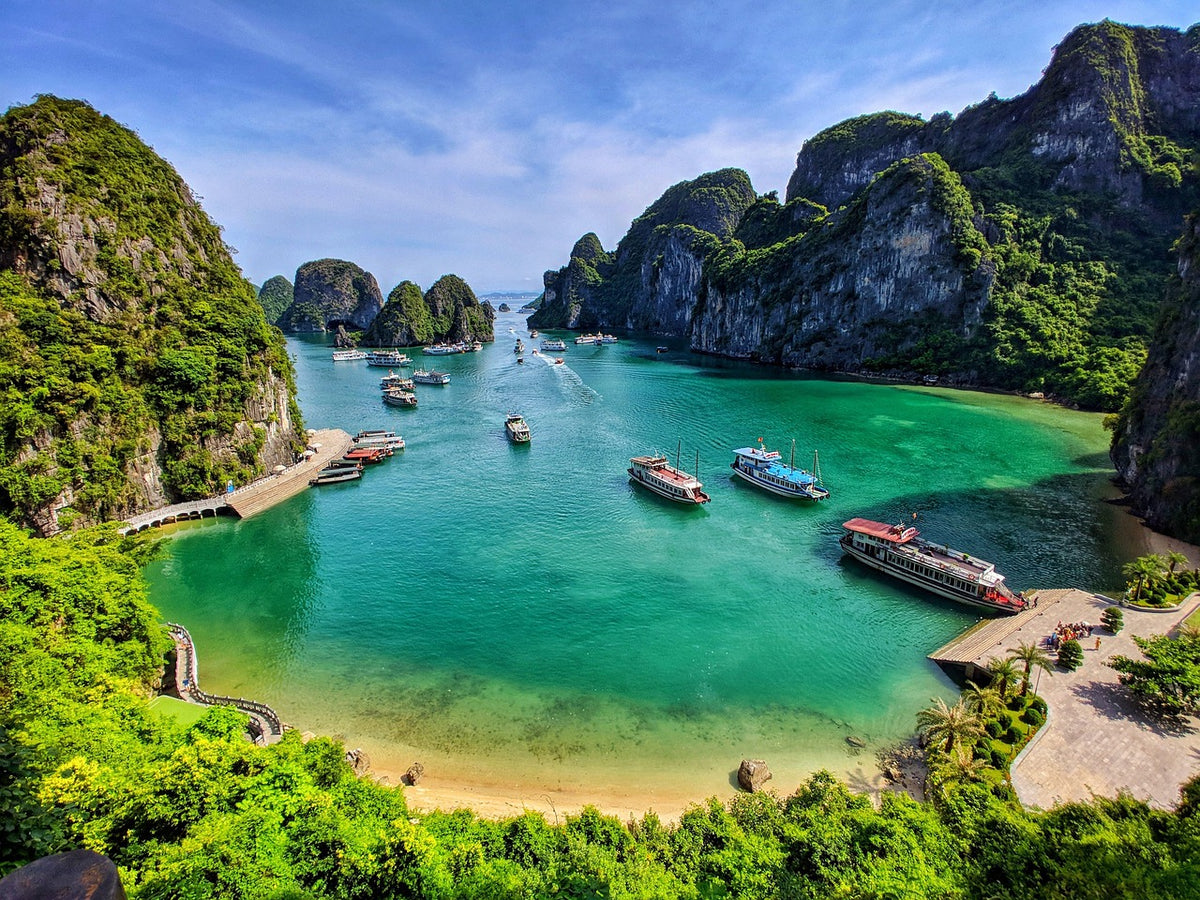 Emerald bay dotted with boats beneath towering green limestone karsts
