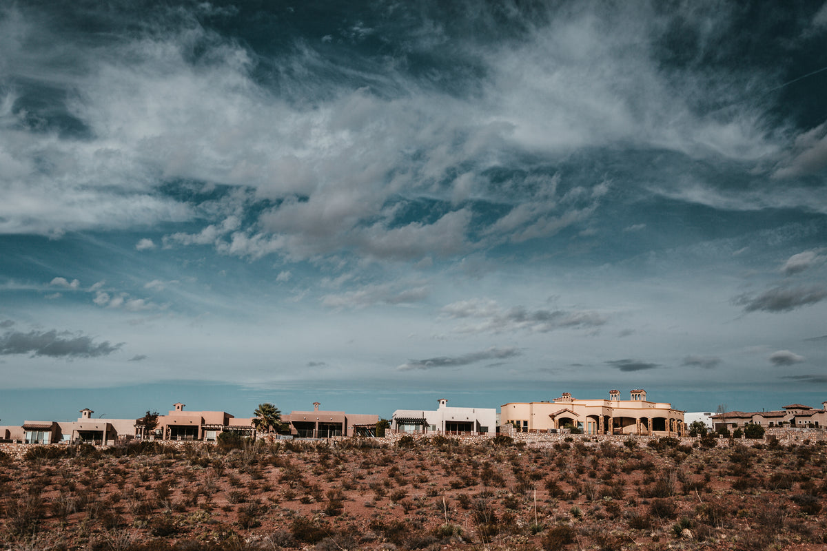 Row of low desert houses under a dramatic cloudy sky