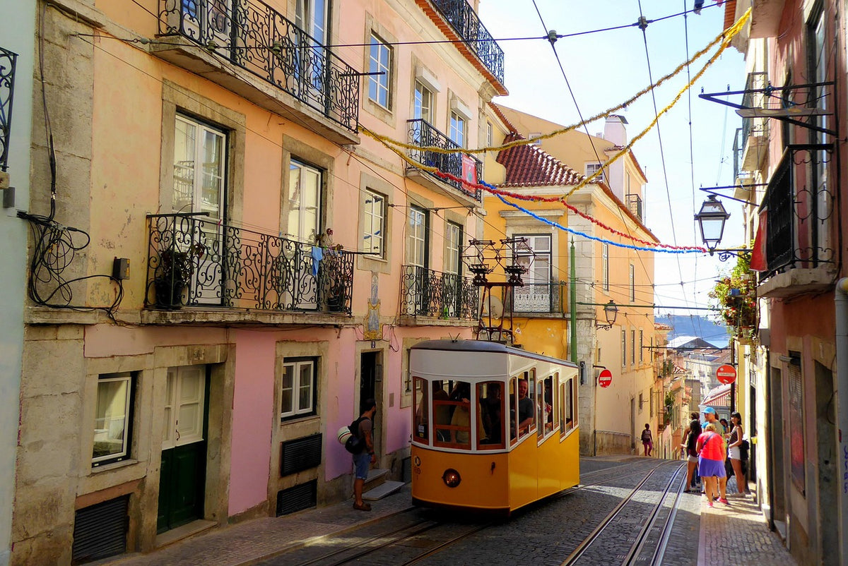 Yellow vintage tram climbing a narrow street of old buildings