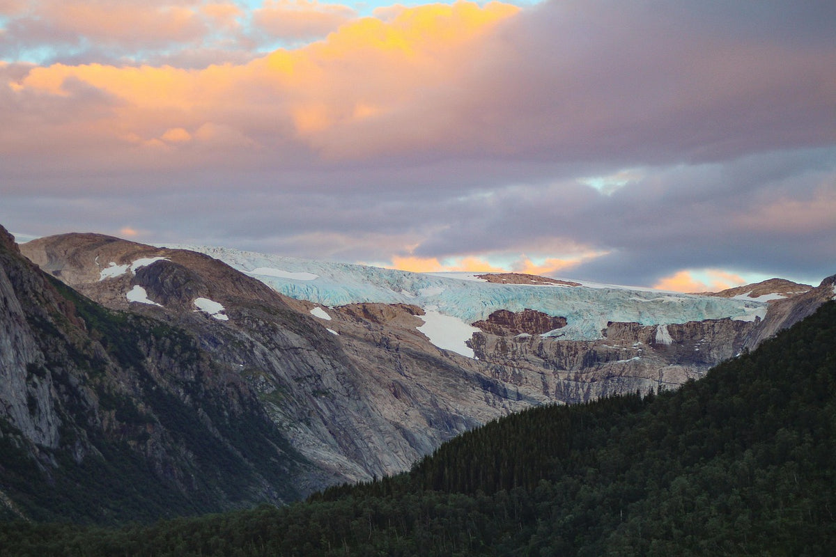 Glacier-streaked mountains under a pink and orange sunset sky