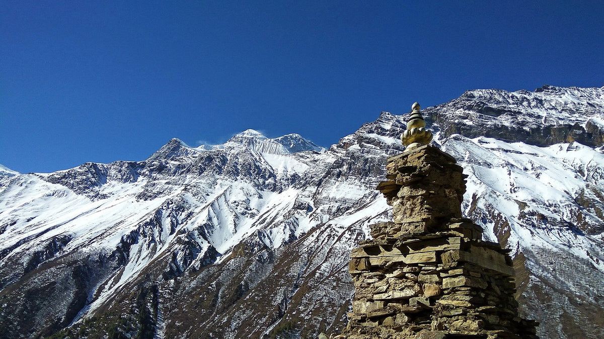 Stone cairn stupa before a range of snow-capped mountain peaks