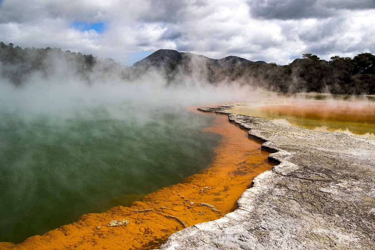 Steaming geothermal pool with a bright orange mineral rim