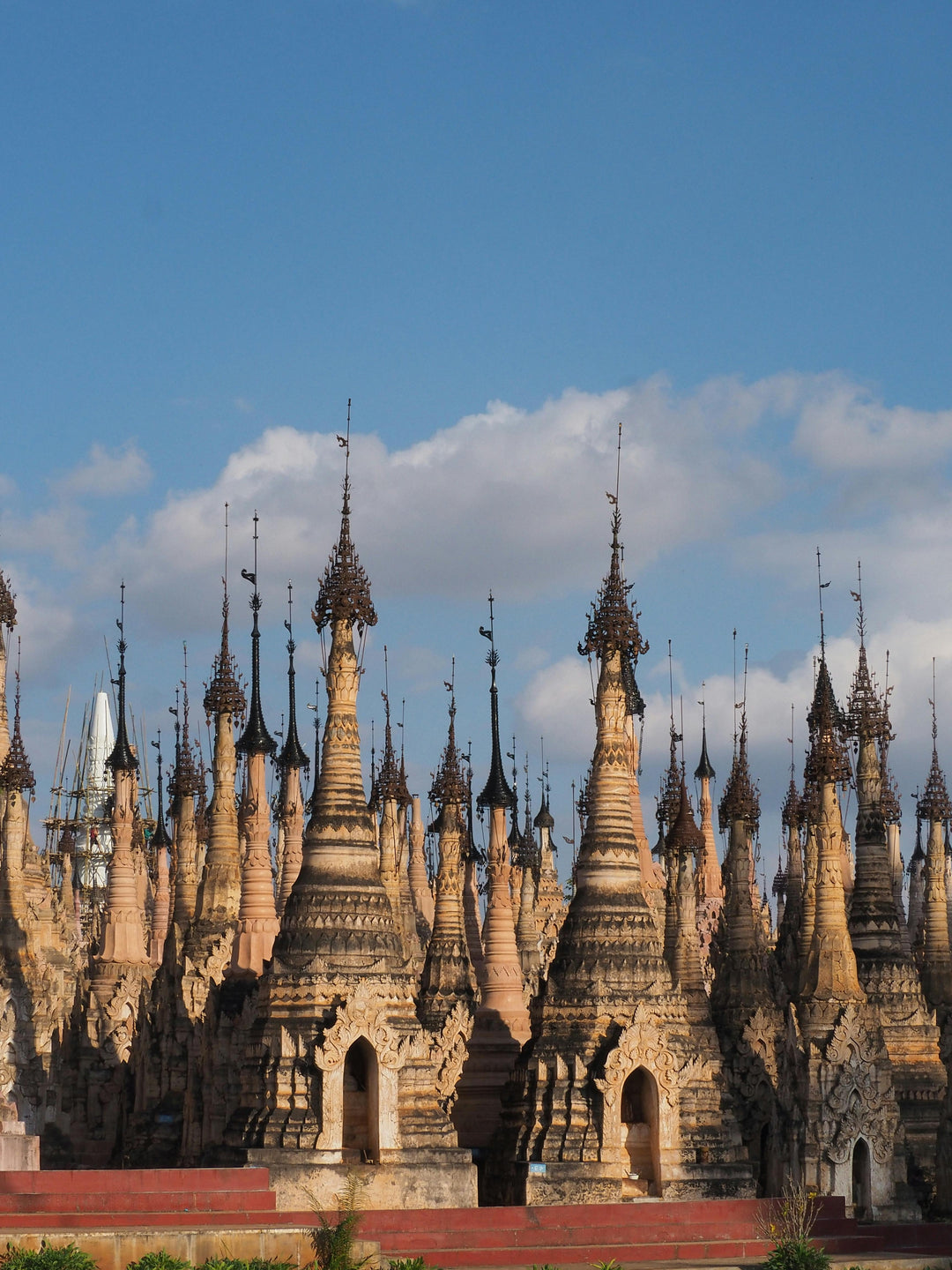 Forest of weathered stone stupas with pointed spires against a cloudy sky