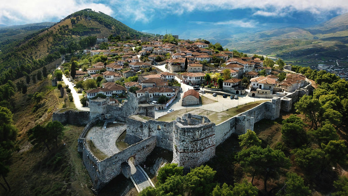 Aerial view of a hilltop stone fortress with red-roofed houses inside