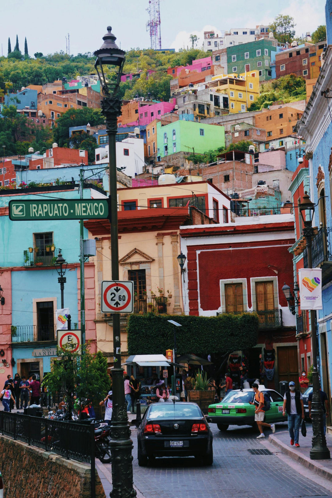 Steep street of colourful houses with lampposts and cars