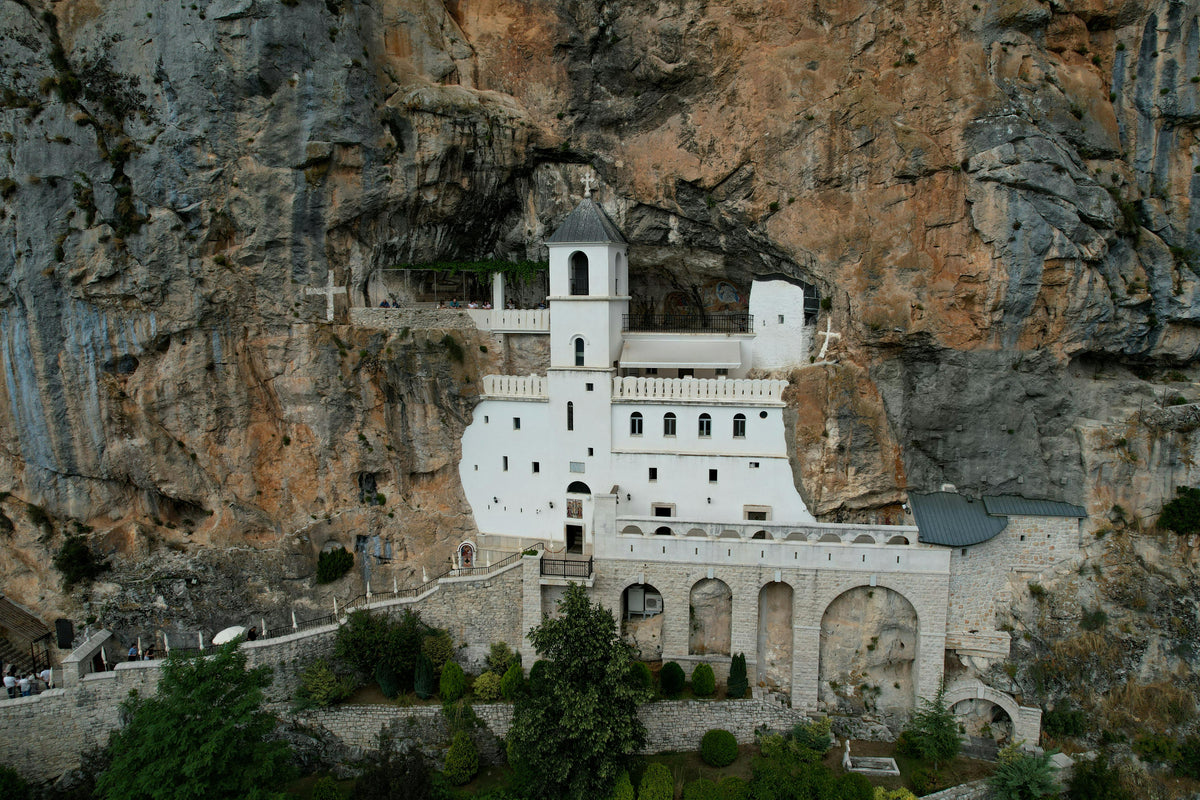 White monastery built into a sheer rock cliff face