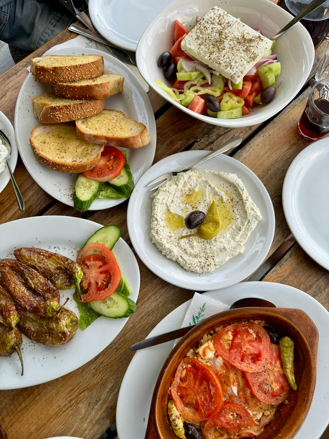 Table of Greek mezze with salad, feta, hummus, bread and peppers