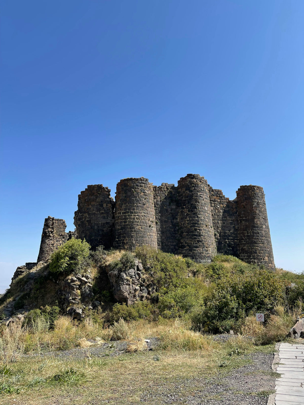 Ruined round stone towers of a fortress on a grassy hill