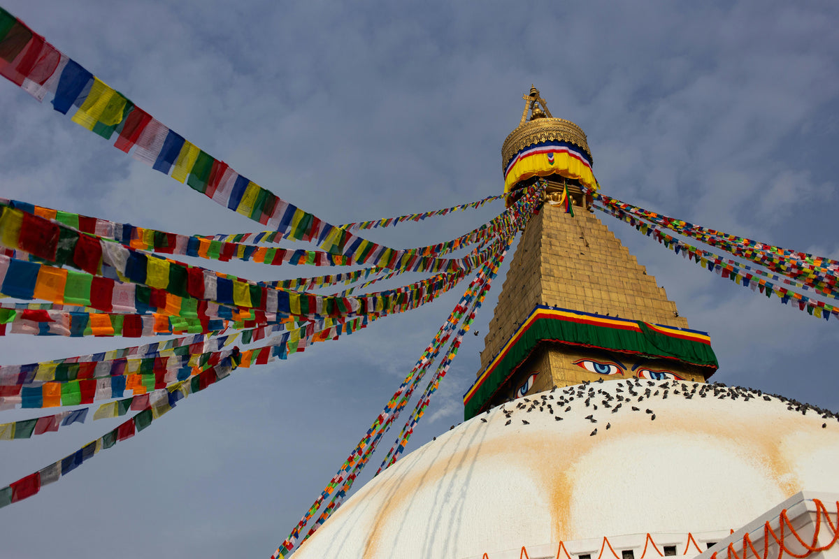 White stupa with golden spire and colourful prayer flags