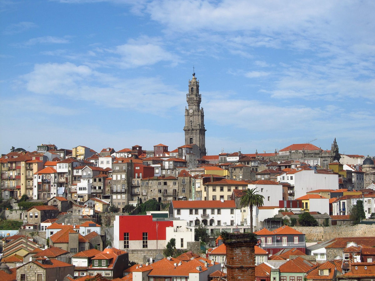 Hillside of red-roofed houses below a tall church bell tower