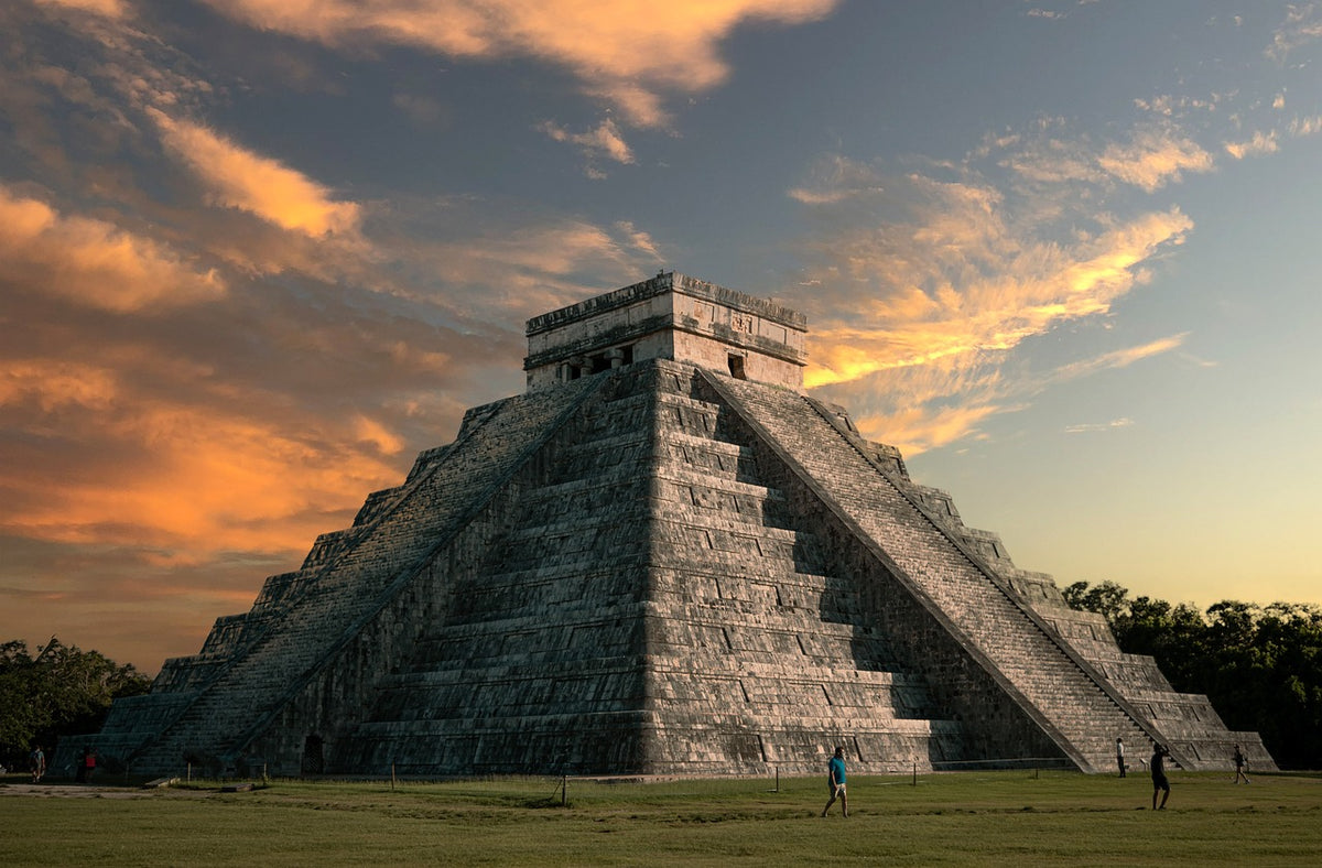 Stepped stone pyramid silhouetted against a golden sunset