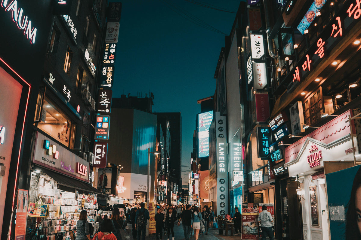 Busy city street at dusk lined with neon signs in Korean script