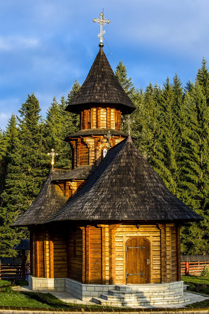 Wooden church with shingled roofs and tower among pine trees