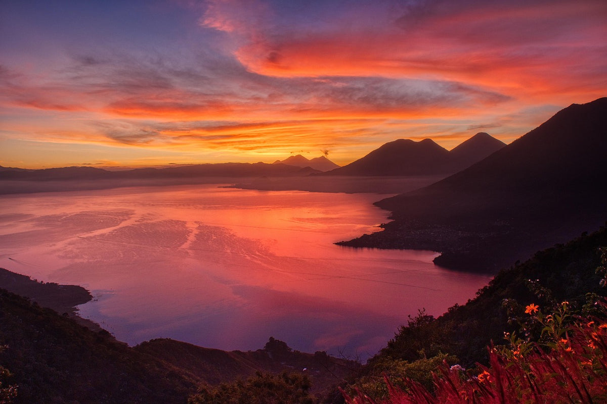Vivid red sunrise over a lake ringed by volcanoes