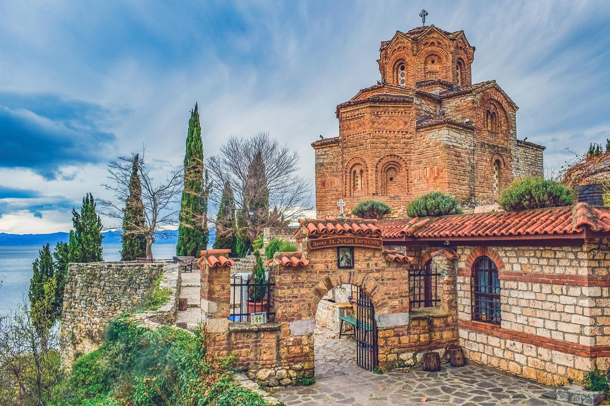 Red brick Byzantine church above a walled garden and lake shore
