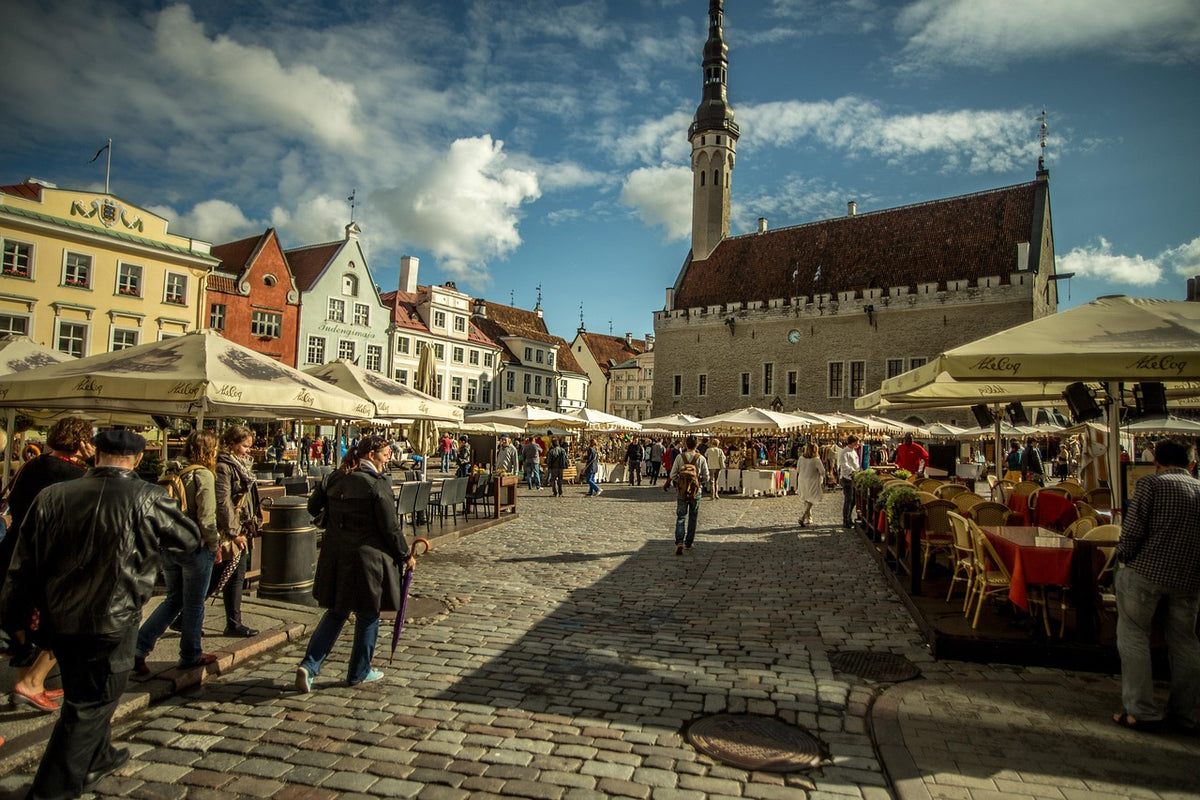 Busy medieval town square with café umbrellas and a Gothic town hall spire