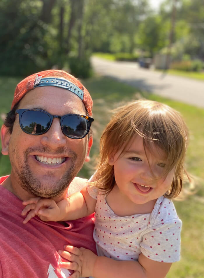 Smiling father in sunglasses with his young daughter outdoors