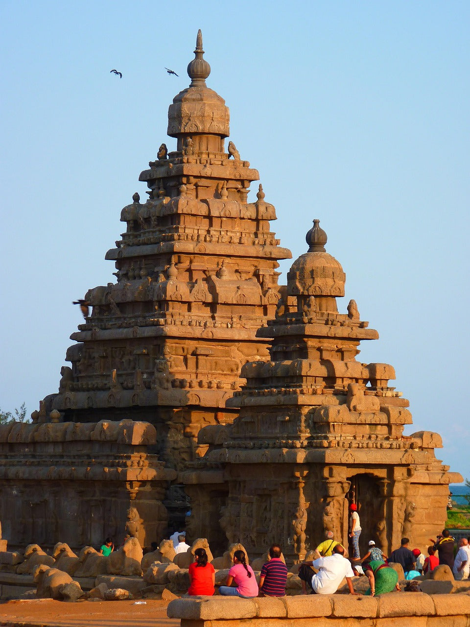 Carved granite temple tower with visitors seated at its base