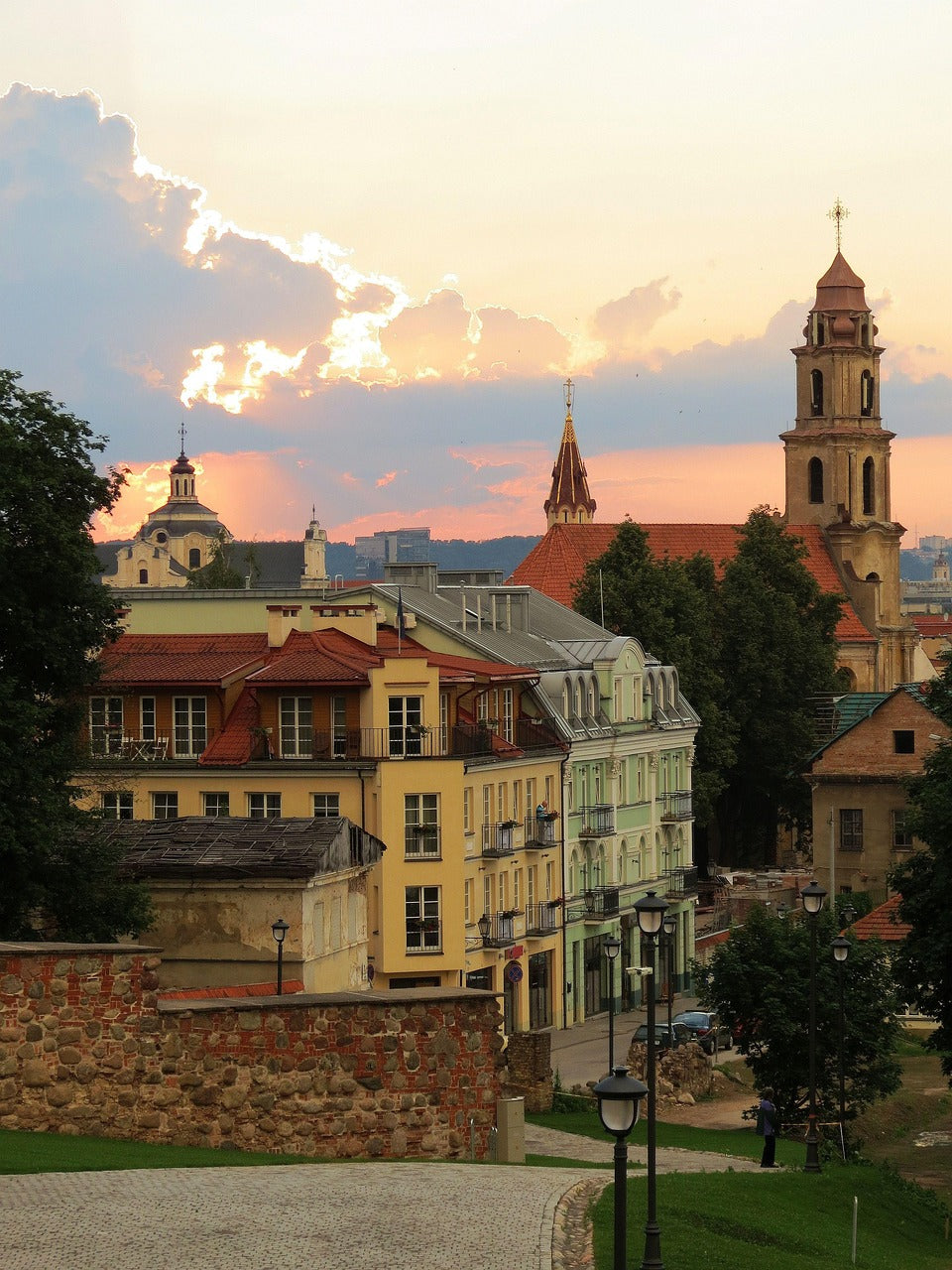 Old town rooftops and church towers glowing under a sunset sky