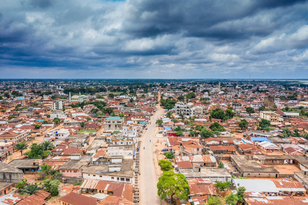 Aerial view of a sprawling town of red roofs under dramatic clouds